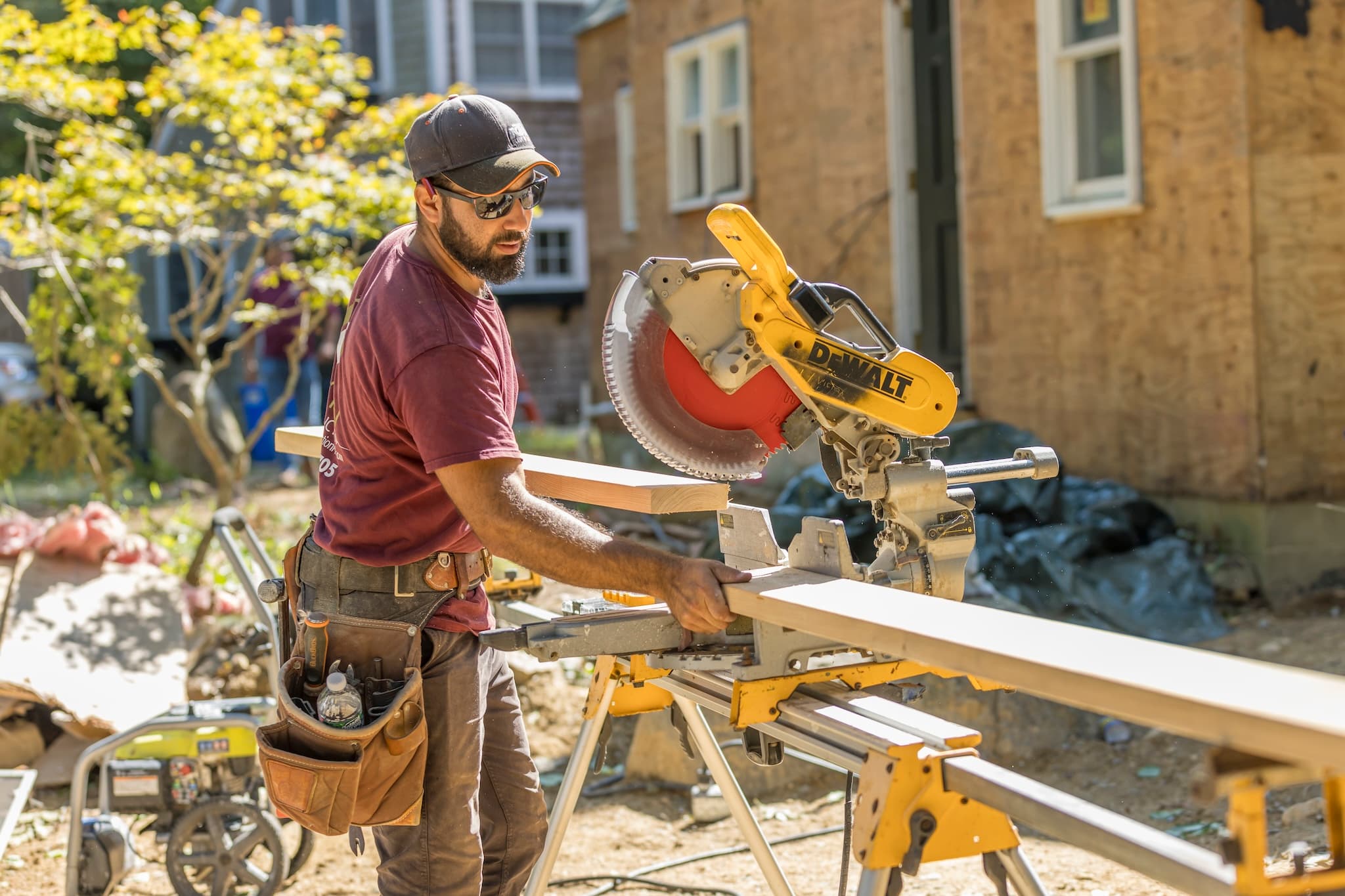 Tekton worker cutting a 2x6 board to length with a chop saw