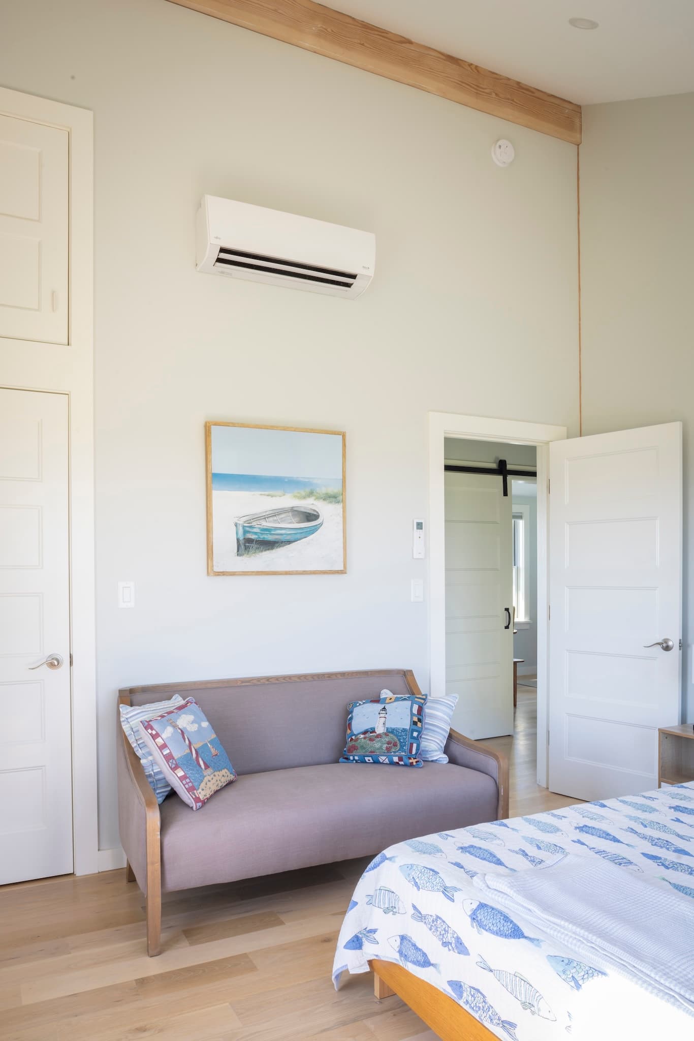 Soft color palette in a private bedroom with mini-split AC unit and exposed rafter
